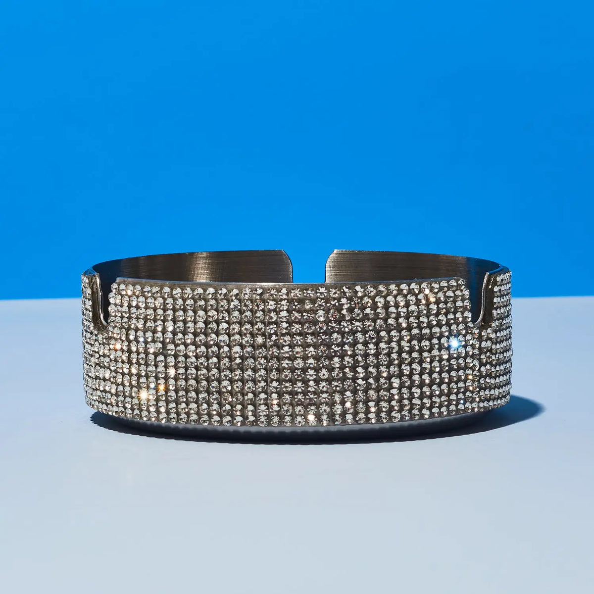 Silver rhinestone ashtray on a blue and gray gradient background
