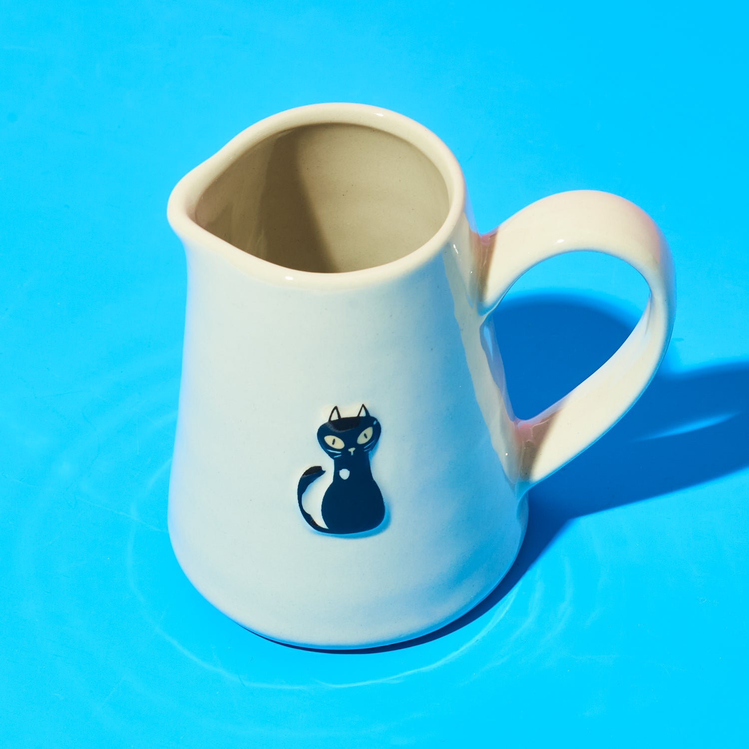 White jug with a blue cat illustration on a blue background