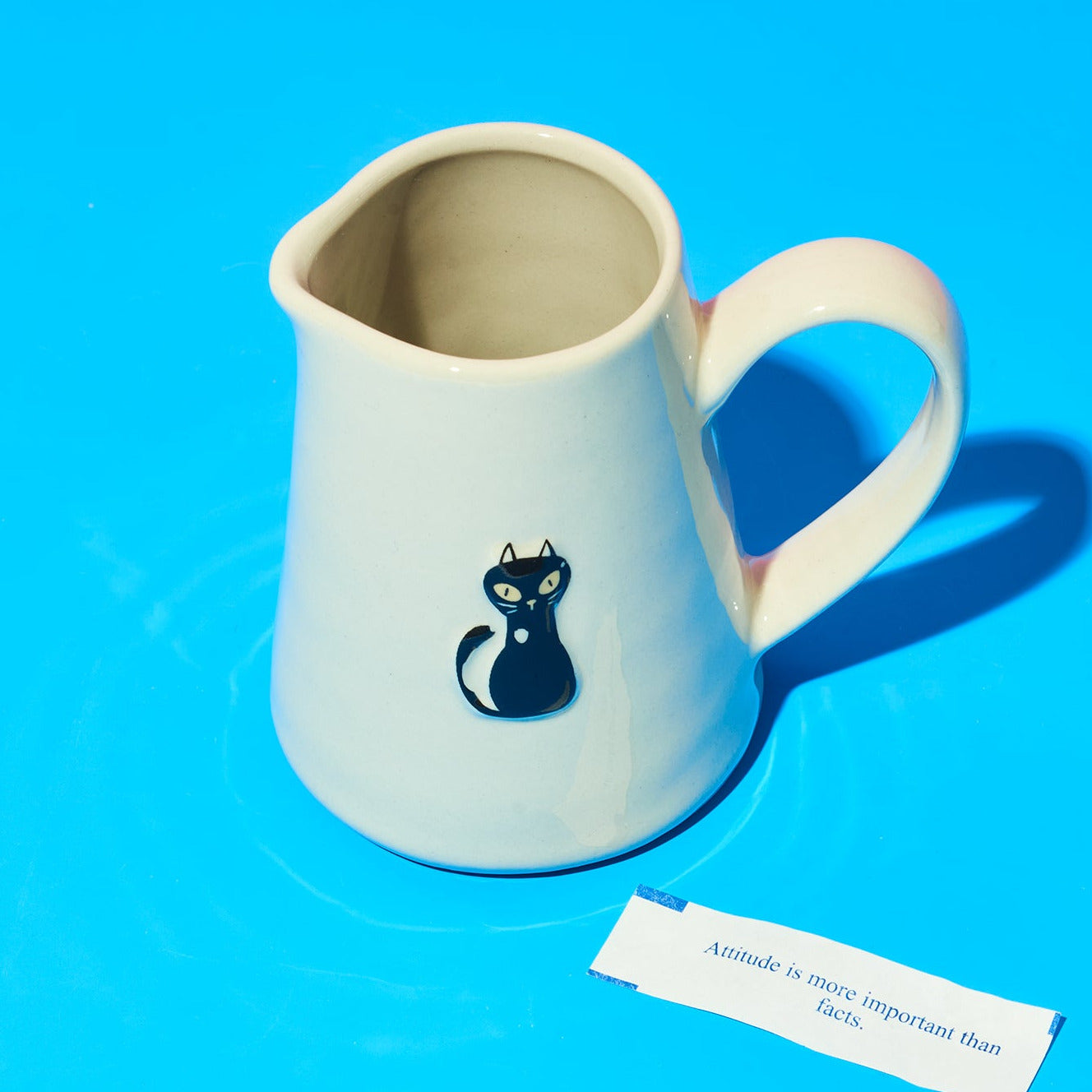 White ceramic pitcher with a blue cat design on a blue background