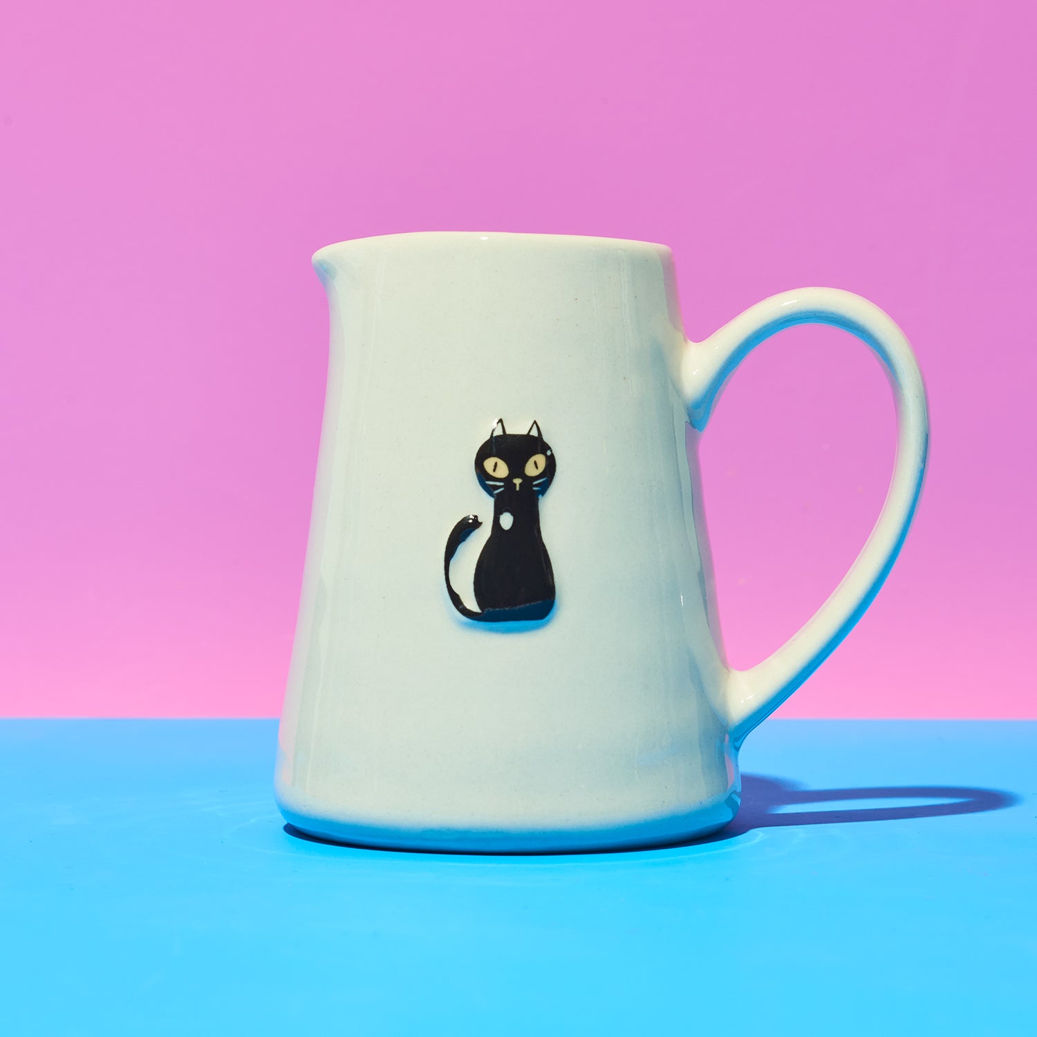 White jug with a black cat illustration on a pink and blue gradient background