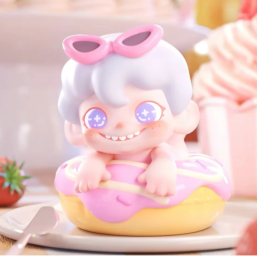Cute figurine with pink sunglasses and white hair sitting on a pink donut with a blurred background.