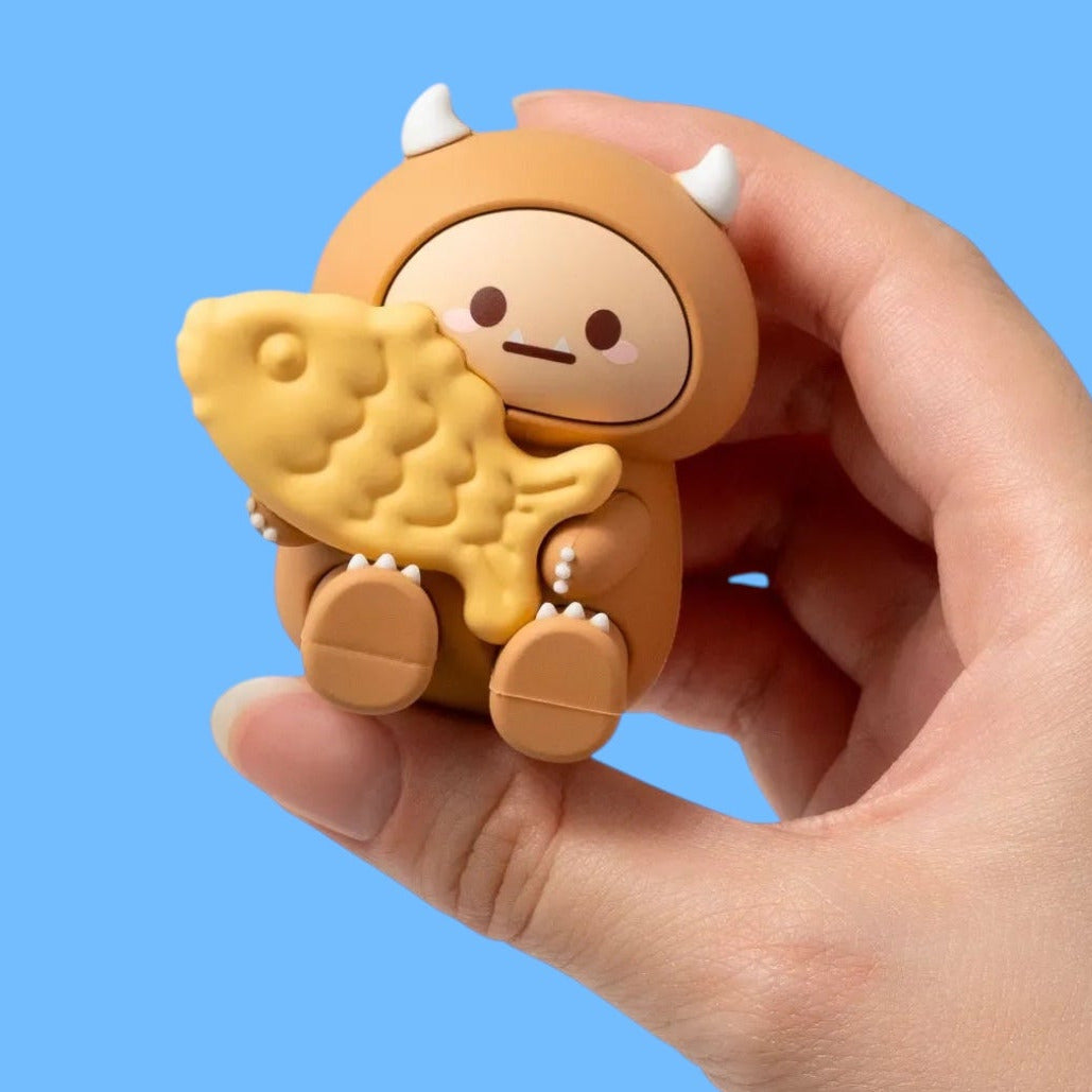 Hand holding a small toy figure with a blue background