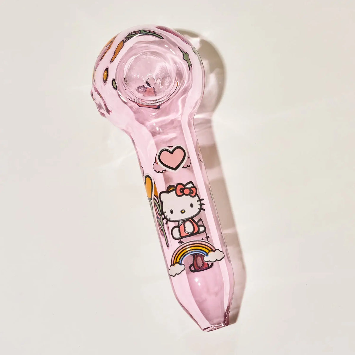 A pink glass hand pipe featuring Hello Kitty illustrations, including a heart, balloons, and a rainbow, shown on a plain off-white background.