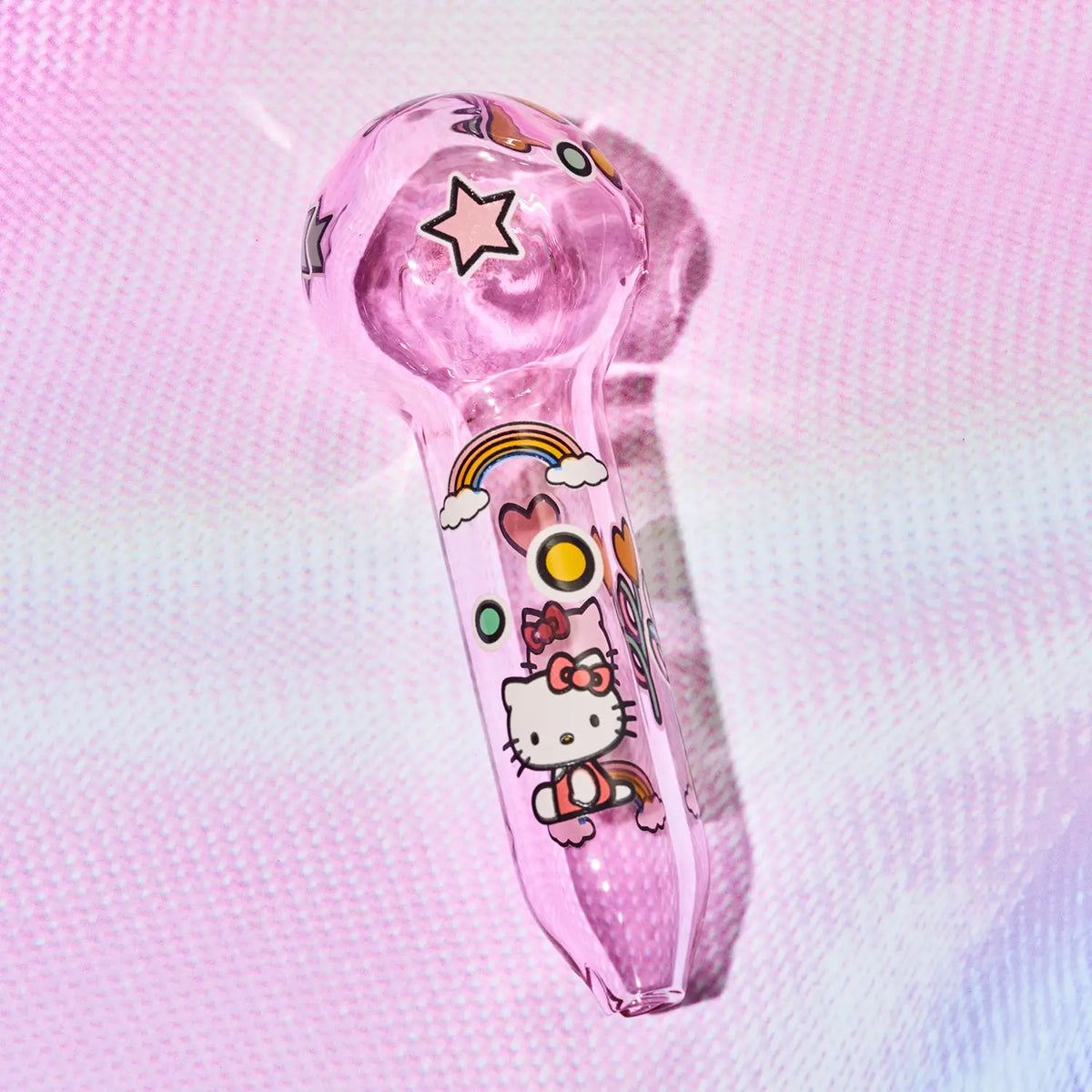A pink glass water pipe decorated with Hello Kitty illustrations, including a rainbow, sun, clouds, and stars, set against a pink textured background.