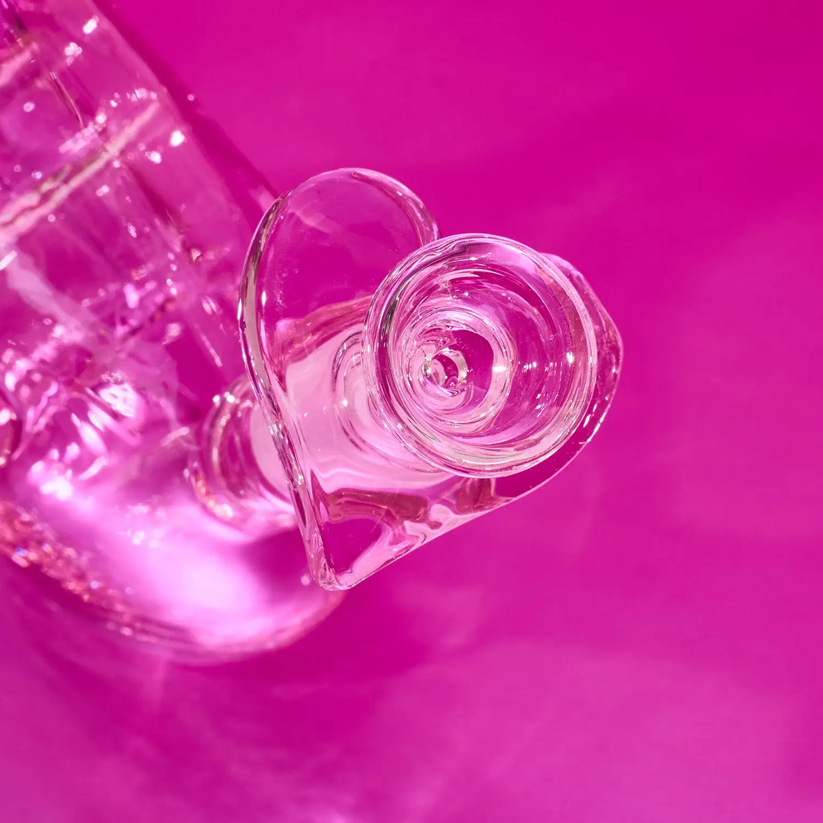 Clear glass heart-shaped object on a pink background