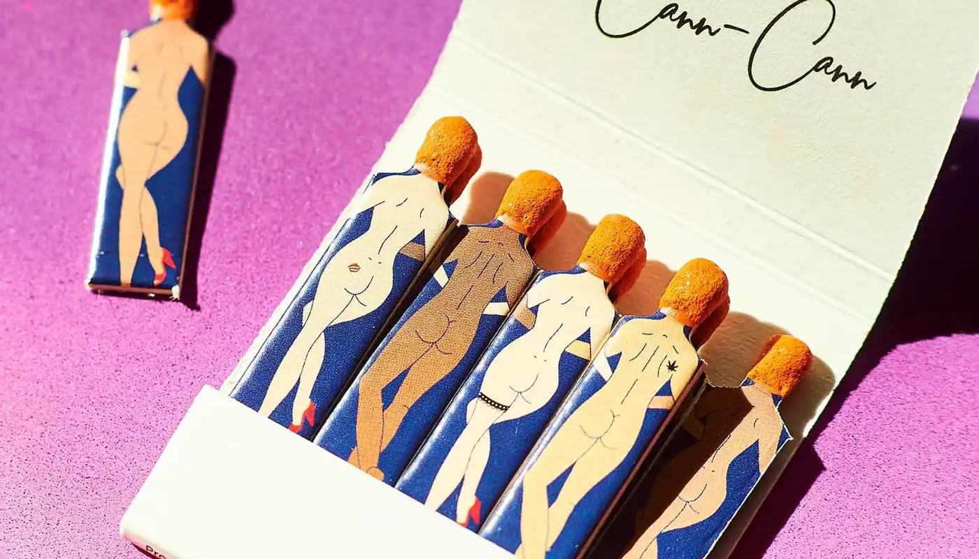 A matchbook featuring illustrated nude figures in blue and beige colors.