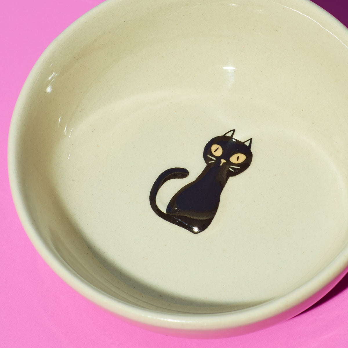 Ceramic bowl with a black cat illustration on a pink background