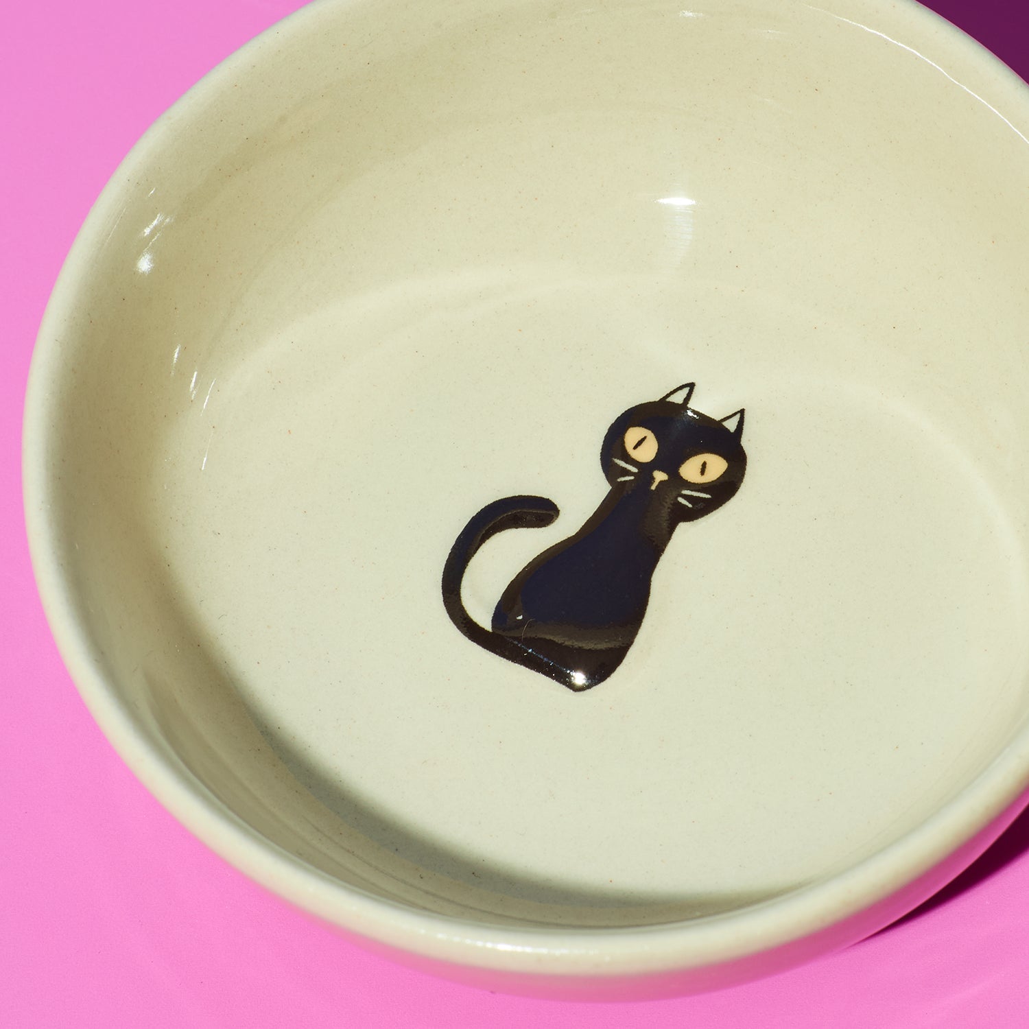 Ceramic bowl with a black cat illustration on a pink background