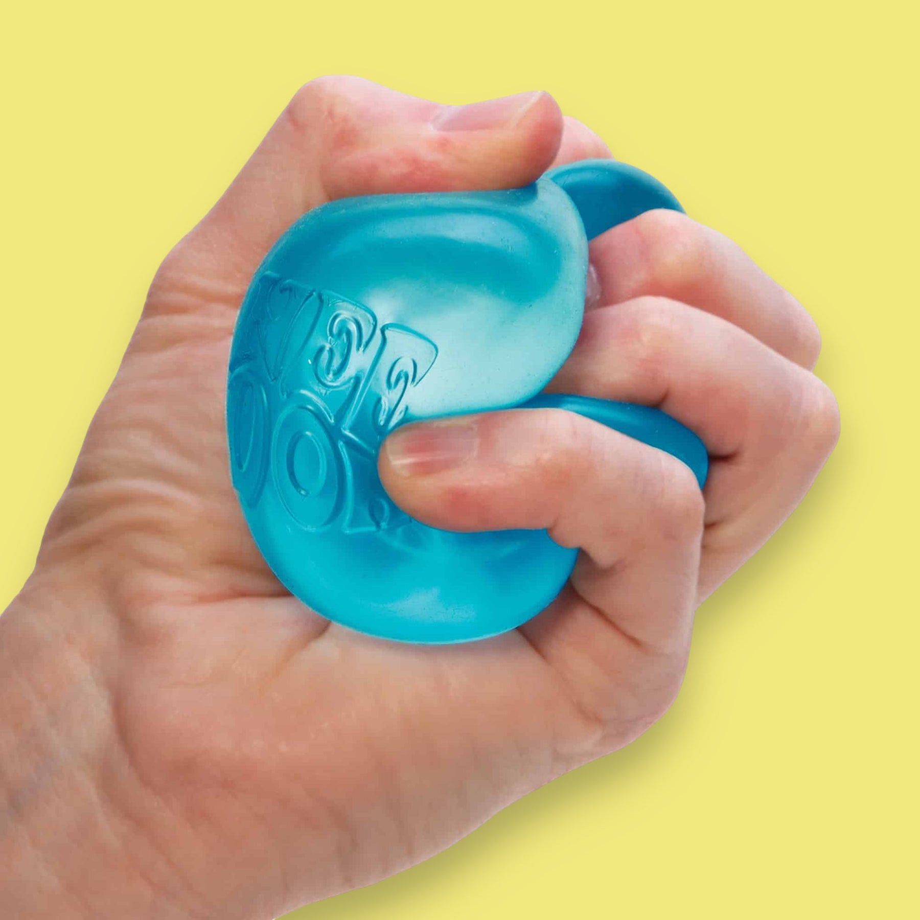 Hand holding a blue stress ball against a yellow background
