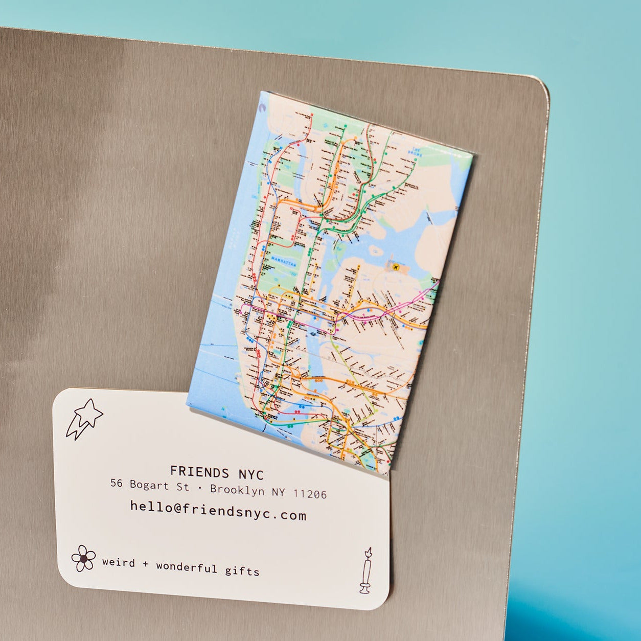 Map of New York City on a card with 'Friends NYC' contact information on a metallic surface.