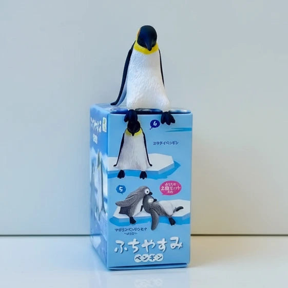 Penguin figurine on top of a blue packaging box with penguin illustrations.