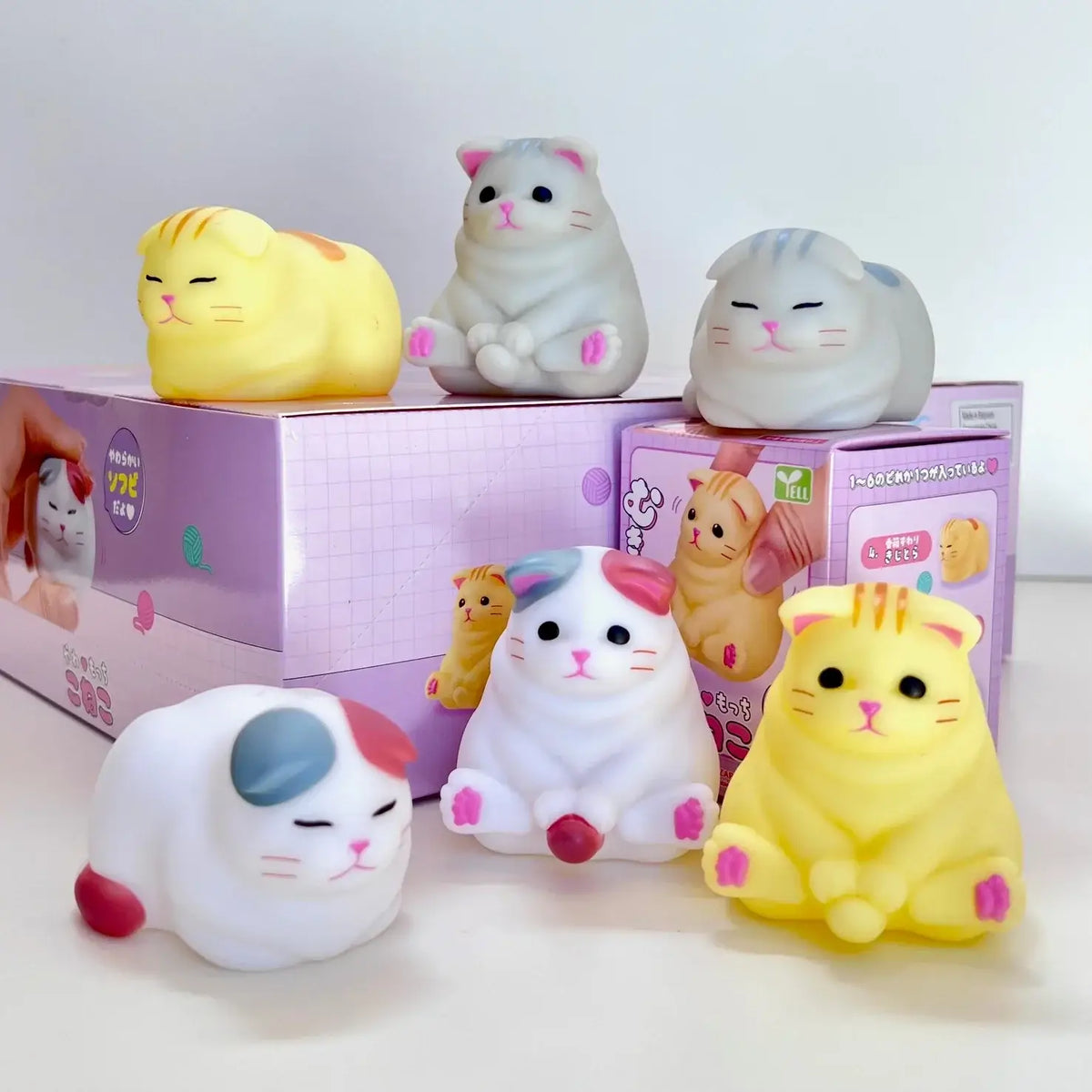 Set of cute cat-shaped squishies with packaging in the background