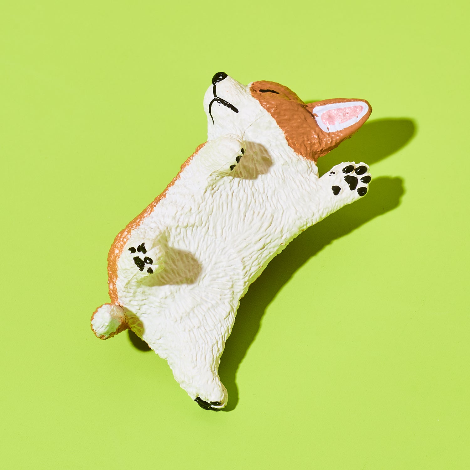 Plastic toy shaped like a corgi on a green background