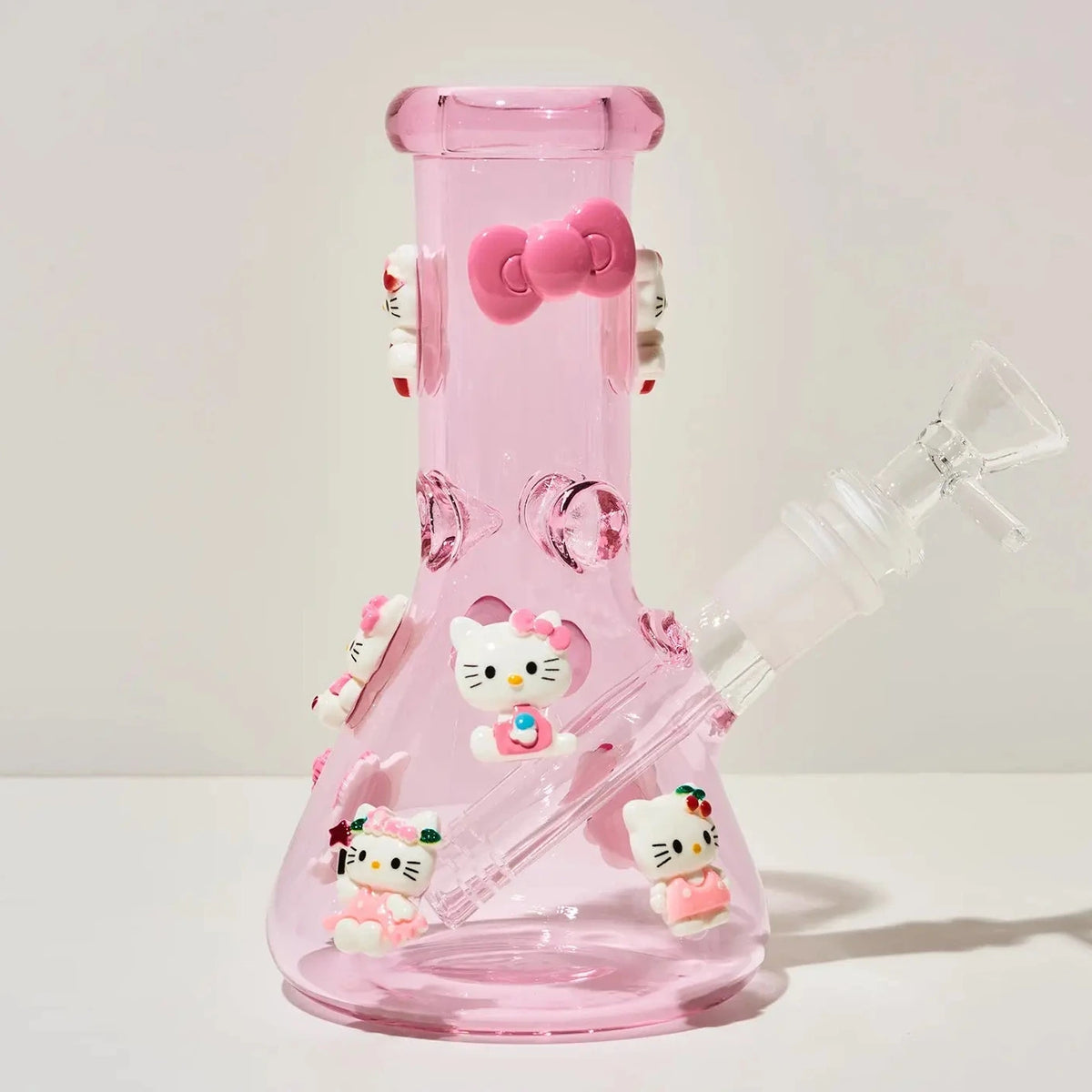 A pink glass beaker-style water pipe decorated with Hello Kitty character figures and bows, shown on a plain light background.