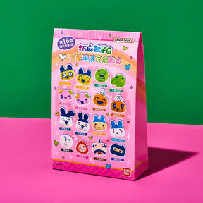A pink paper bag package of Bandai Namco 'Mochi Dango Q' collectible blind boxes, standing on a pink surface against a green background.