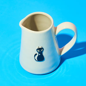 White jug with a blue cat illustration on a blue background