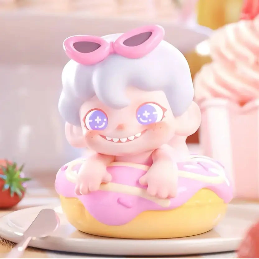 Cute figurine with pink sunglasses and white hair sitting on a pink donut with a blurred background.