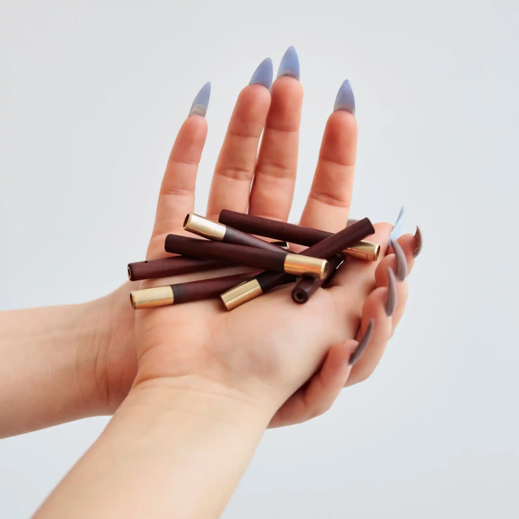 Hands with blue painted nails holding chocolate wafer sticks.