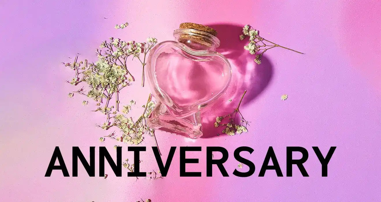 Heart-shaped glass bottle with a cork stopper and delicate white flowers beside it.