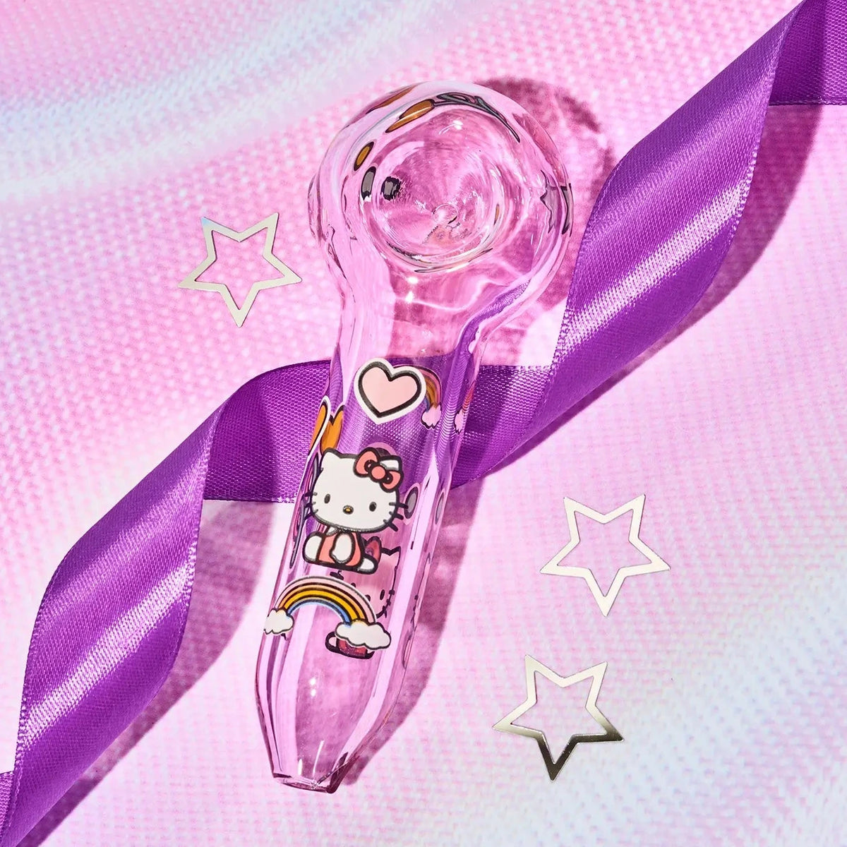 A pink transparent glass hand pipe decorated with Hello Kitty illustrations, wrapped with a purple satin ribbon on a pink textured background with star-shaped accents.