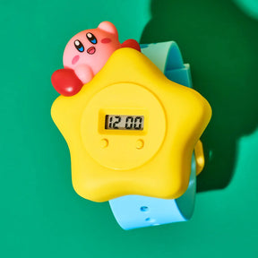 Toy figure of a Kirby on top of a yellow star-shaped watch with a digital display on a green background