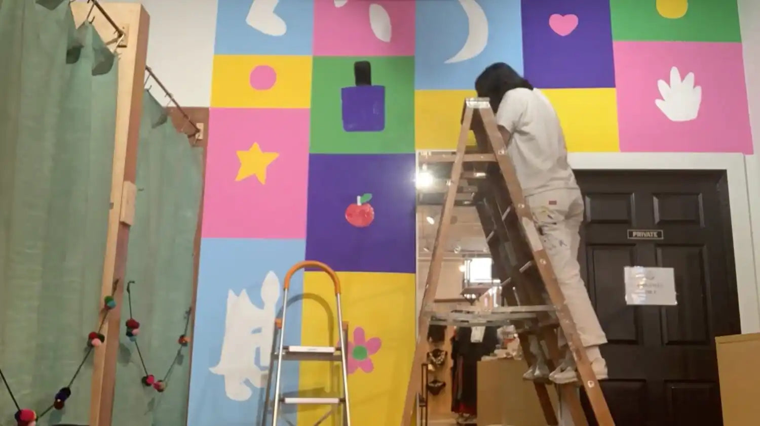 Ladder leaning against a colorful patchwork wall.