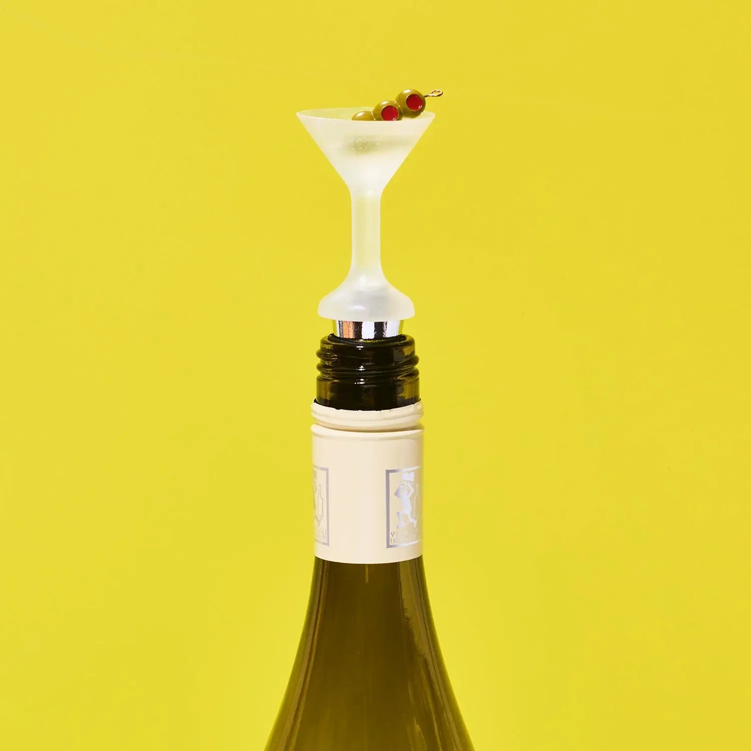 Wine bottle with a novelty bottle stopper shaped like a cocktail glass on a yellow background