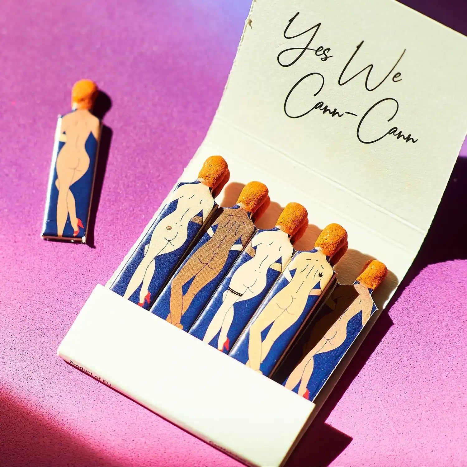 A matchbook featuring illustrated nude figures in blue and beige colors.