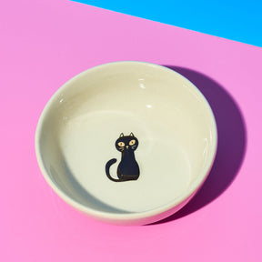 Ceramic bowl with a black cat illustration on a pink and blue background