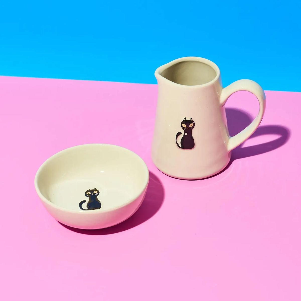 Ceramic mug and bowl with cat design on a pink and blue background