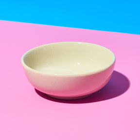 Beige bowl on a pink surface with a blue background