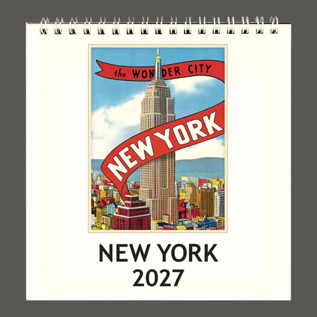 A spiral-bound 2027 New York desk calendar shown flat against a dark gray background. The front cover features a vintage-style travel poster of the Empire State Building with red banners reading 'the WONDER CITY' and 'NEW YORK', plus 'NEW YORK 2027' printed below.