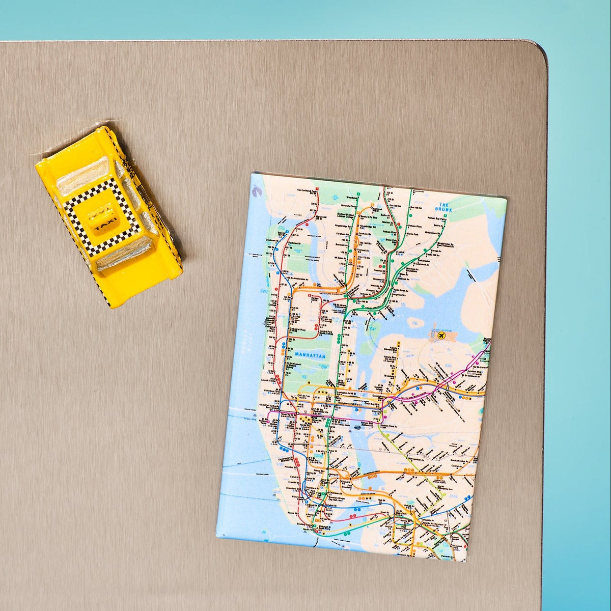 Map of a subway system on a folded piece of paper with a yellow box next to it on a beige surface.