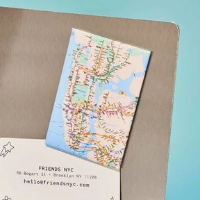Map of New York City on a card with 'Friends NYC' contact information on a metallic surface.
