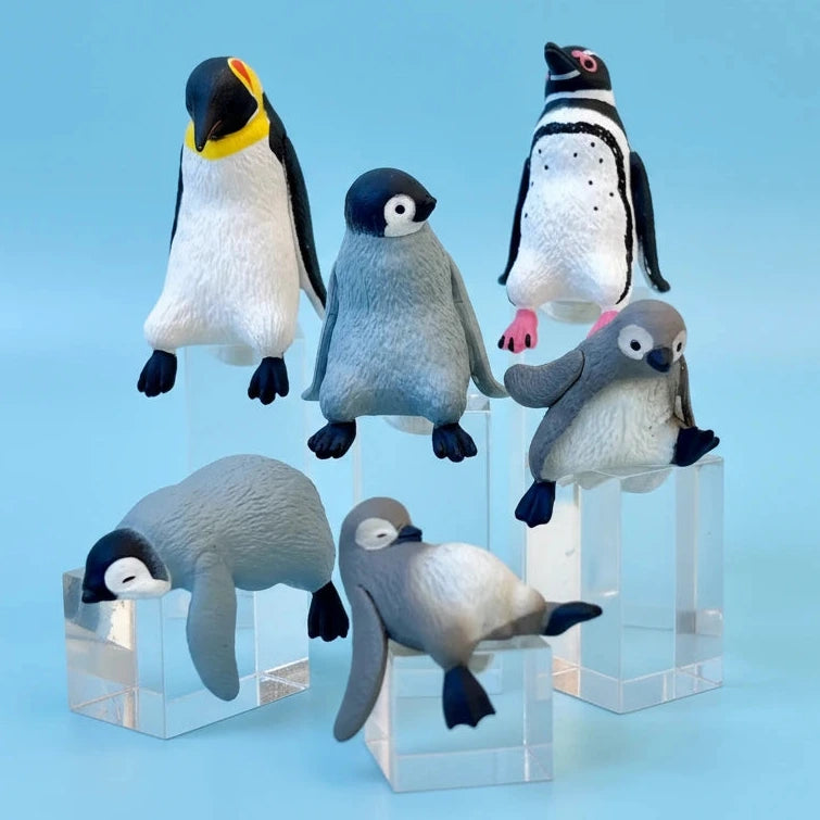 Set of penguin figurines on clear stands against a white background