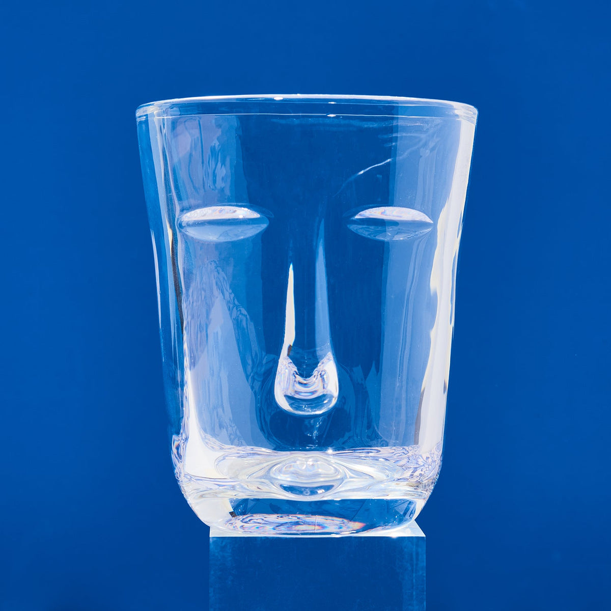 Clear glass with face design on a blue background