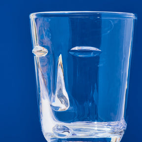 Clear glass tumbler with water droplets on a blue background