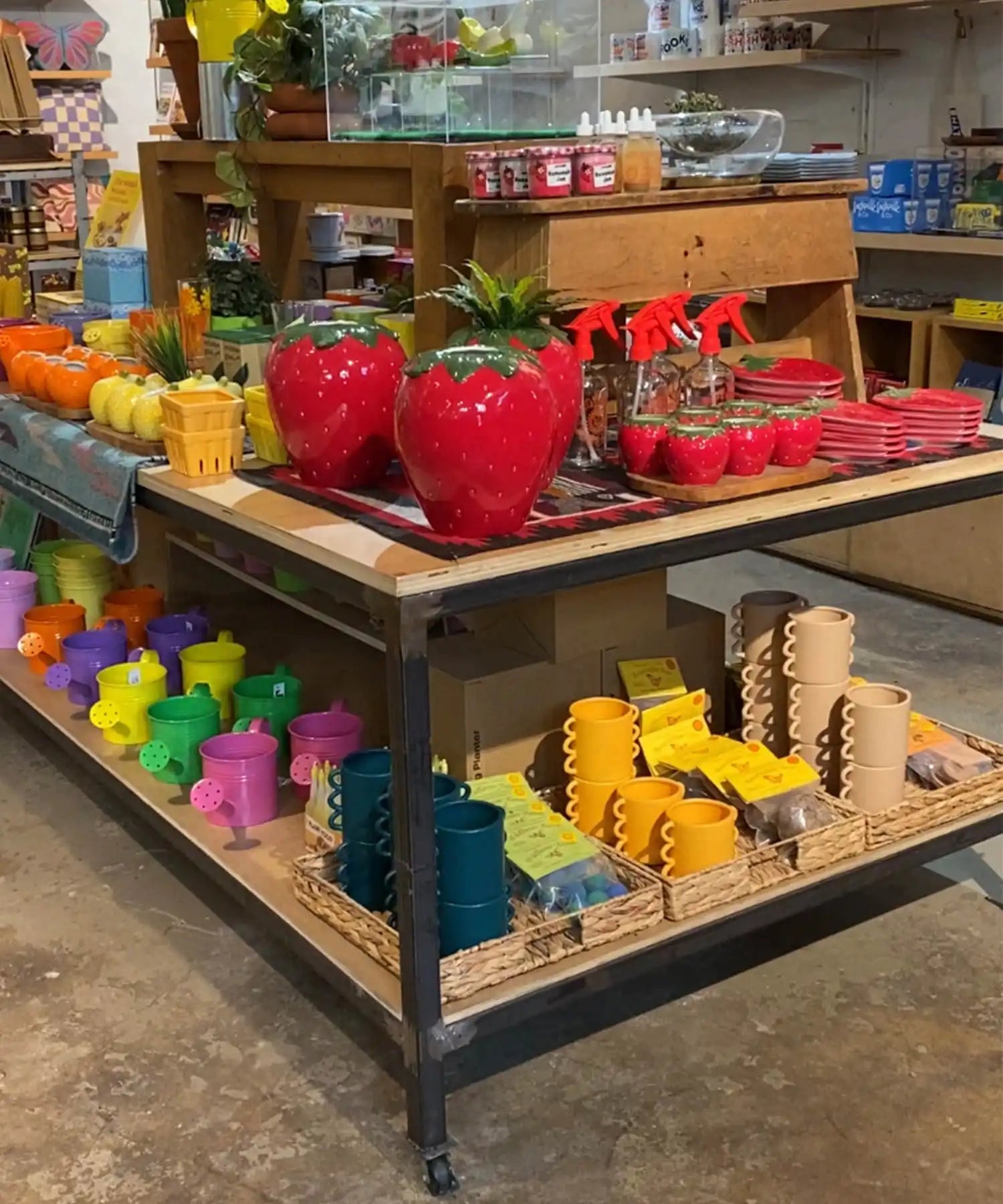 Retail display cart with decorative strawberry containers and colorful garden accessories.