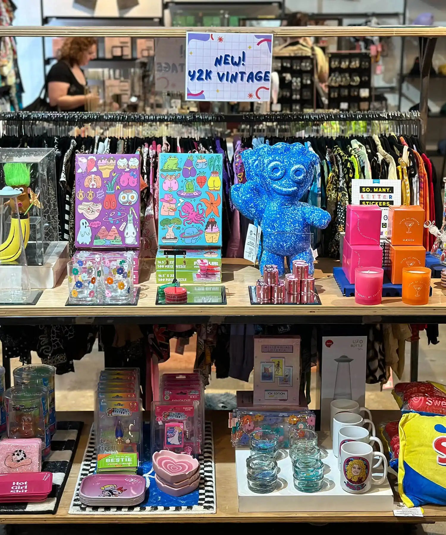 Retail display shelf filled with colorful stationery, notebooks, and plush toys.