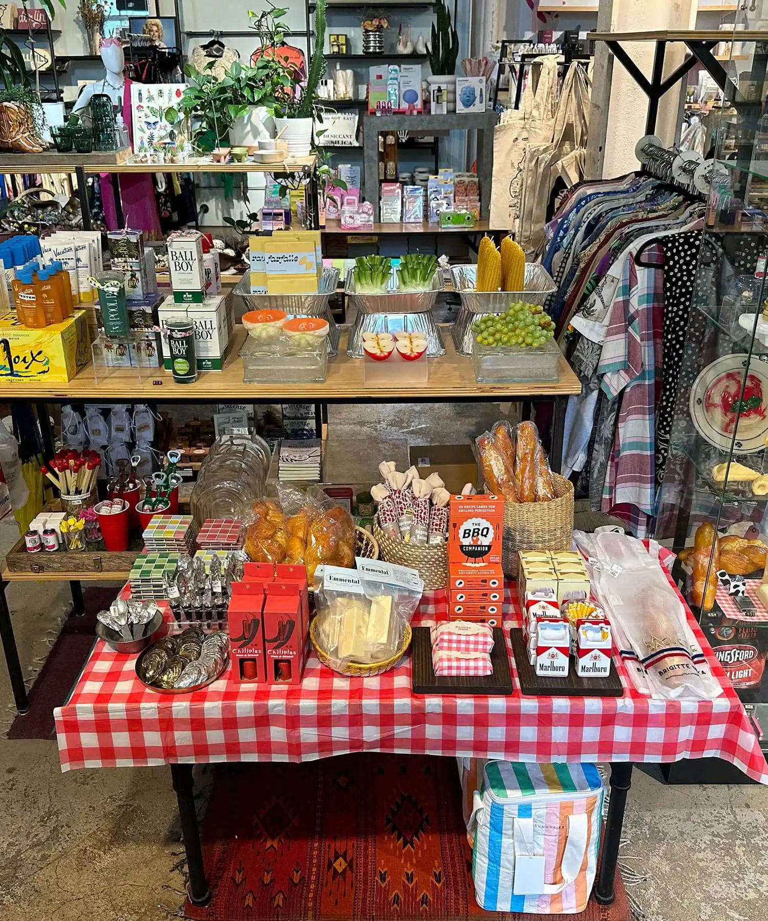 Retail display table with red and white checkered tablecloth showcasing various products and merchandise.