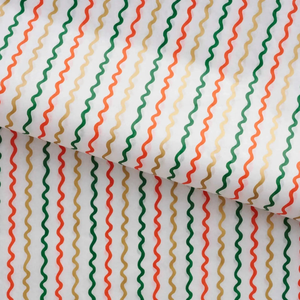 close up of tissue paper with a stylized design of gold, orange and green ribbons