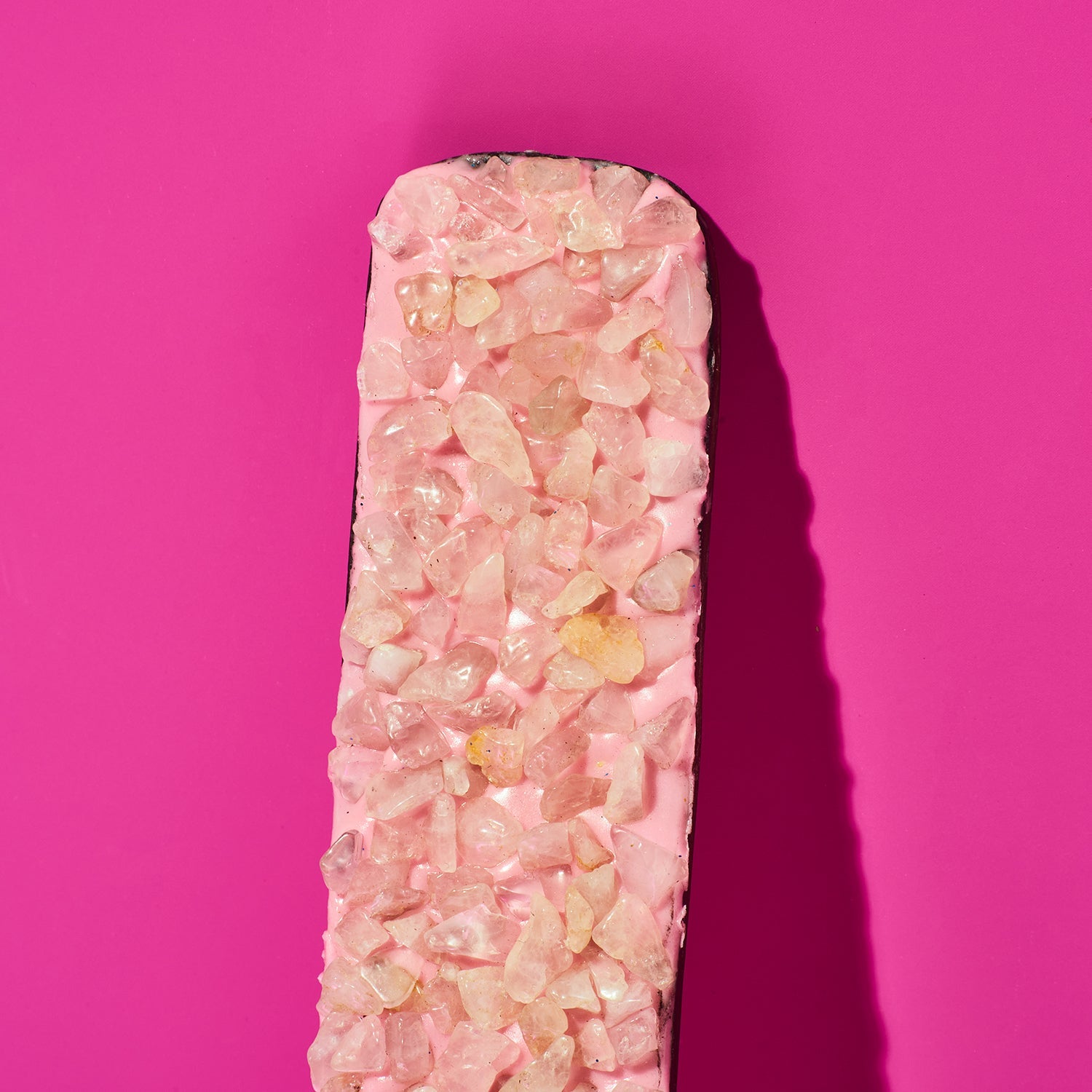Pink crystal bar with embedded stones on a pink background
