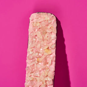 Pink crystal bar with embedded stones on a pink background