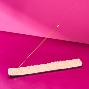 Incense stick burning on a pink background