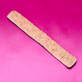 Long rectangular stone slab with small stones on a pink background