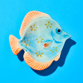 Decorative fish-shaped object with peach and blue design on a blue background
