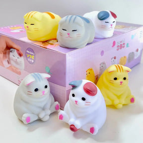 Cat-shaped squishies in front of a pink box with cat illustrations.