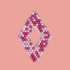 Pink and white beaded heart-shaped object on a light pink background