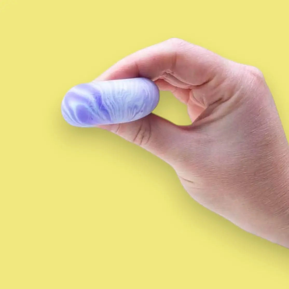 Hand holding a marbled purple and blue object against a yellow background