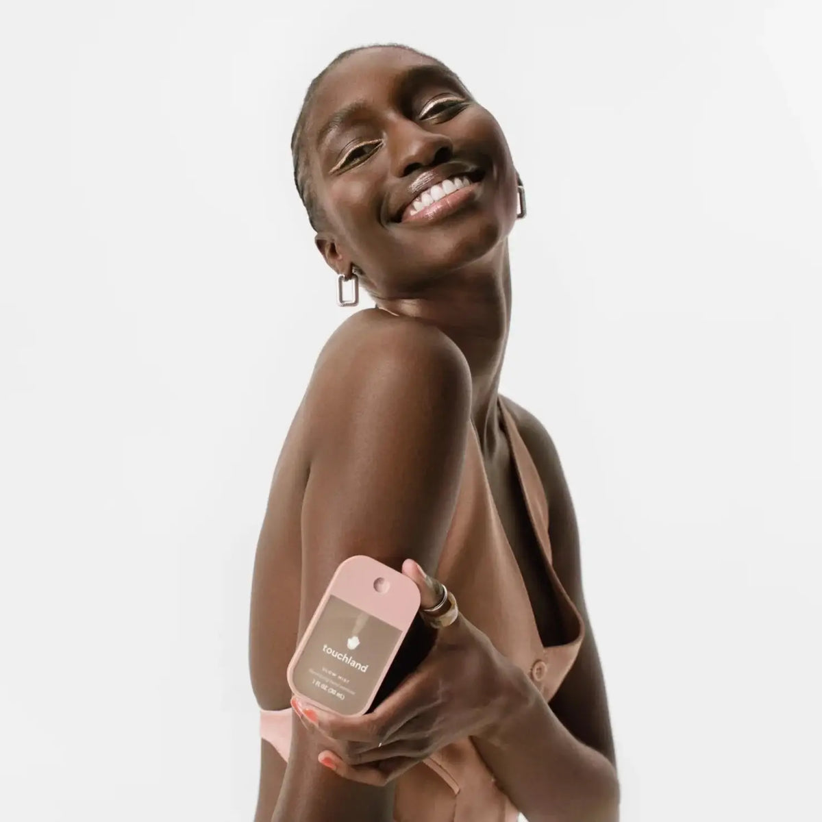 Woman holding a pink hand sanitizer against a white background